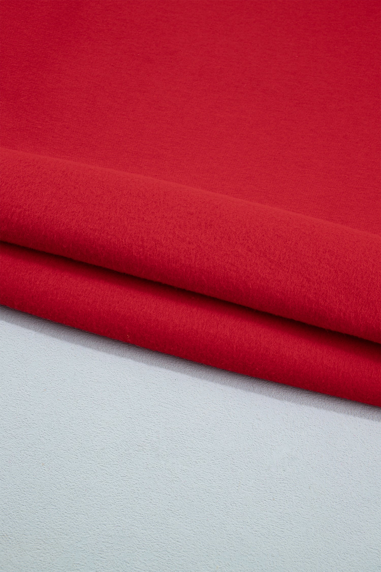A close-up of folded red fabric resting on a light gray surface, showing the material texture and color.