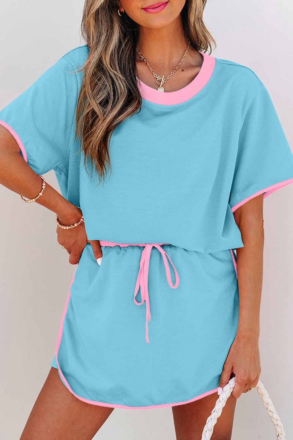 Woman wearing a blue outfit with pink trim against a plain background