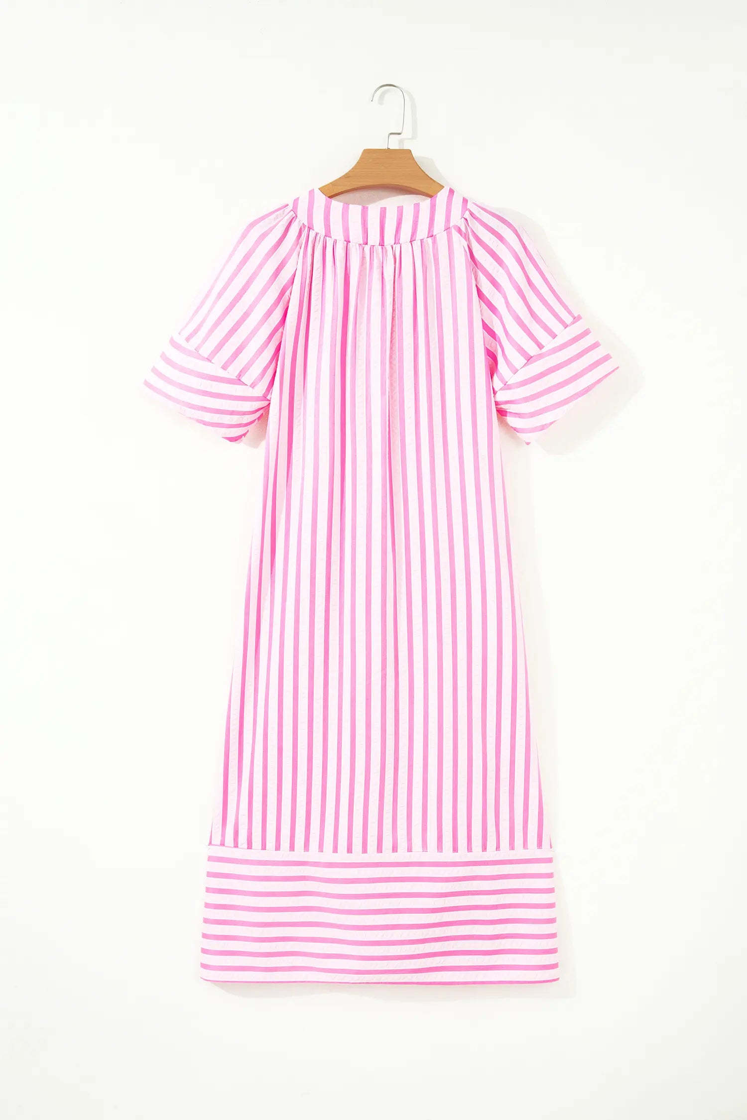 A pink and white vertically striped short-sleeve dress hanging on a wooden hanger against a plain white background.