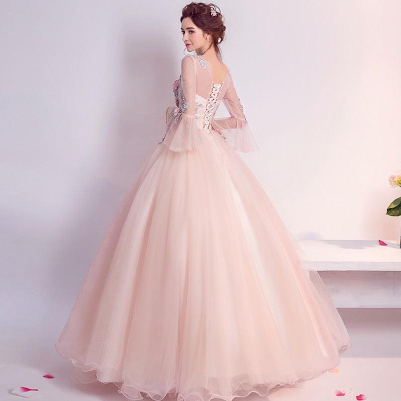 Woman in a pink evening gown standing on a staircase with a white background