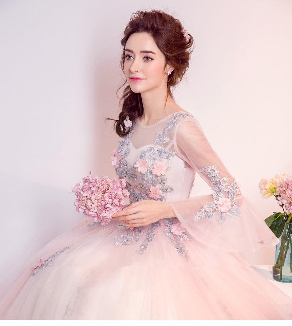 Woman in a pink and silver dress holding flowers against a light background