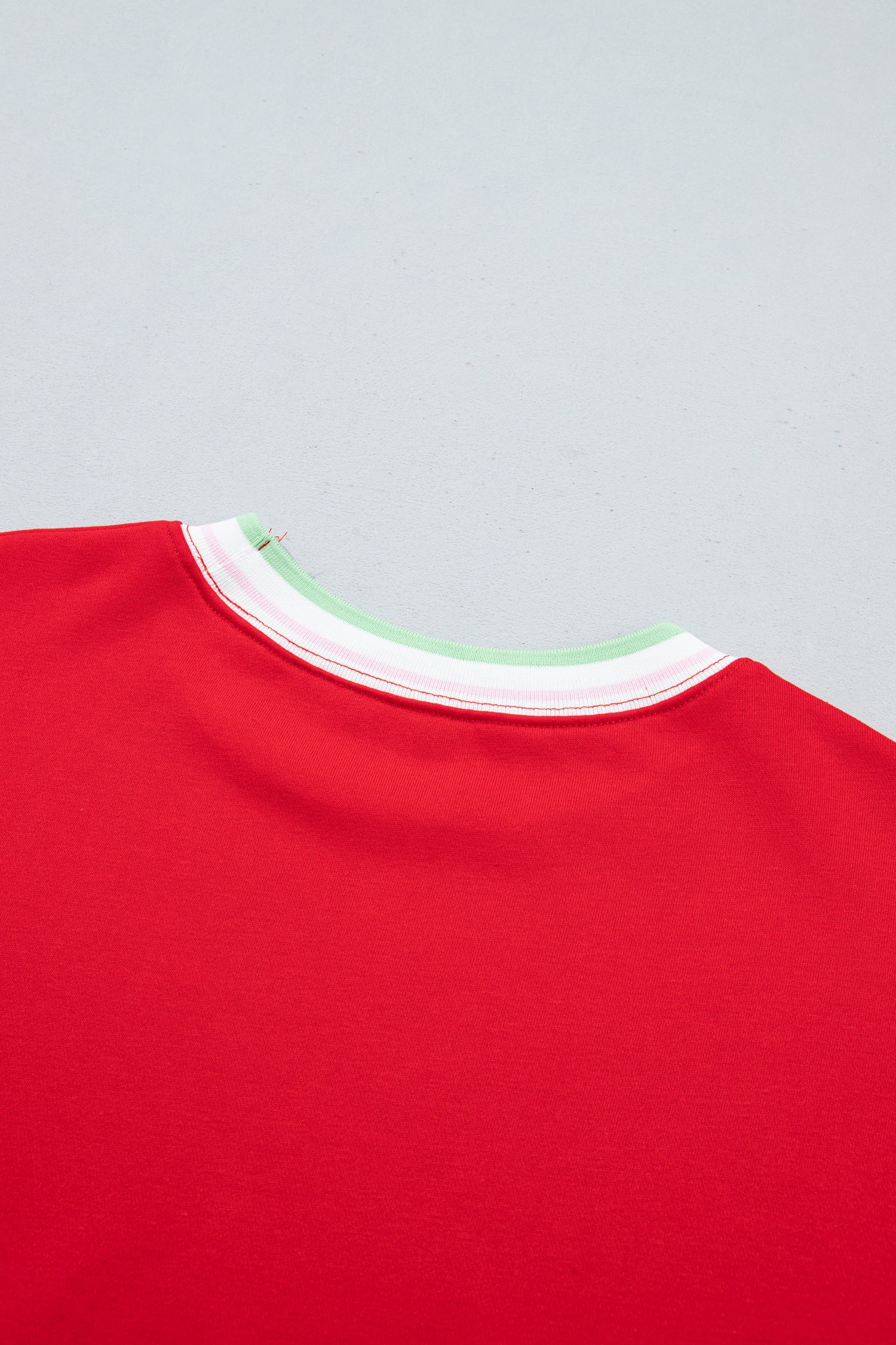 Close-up of the back neckline of a bright red crewneck sweatshirt, showing 
