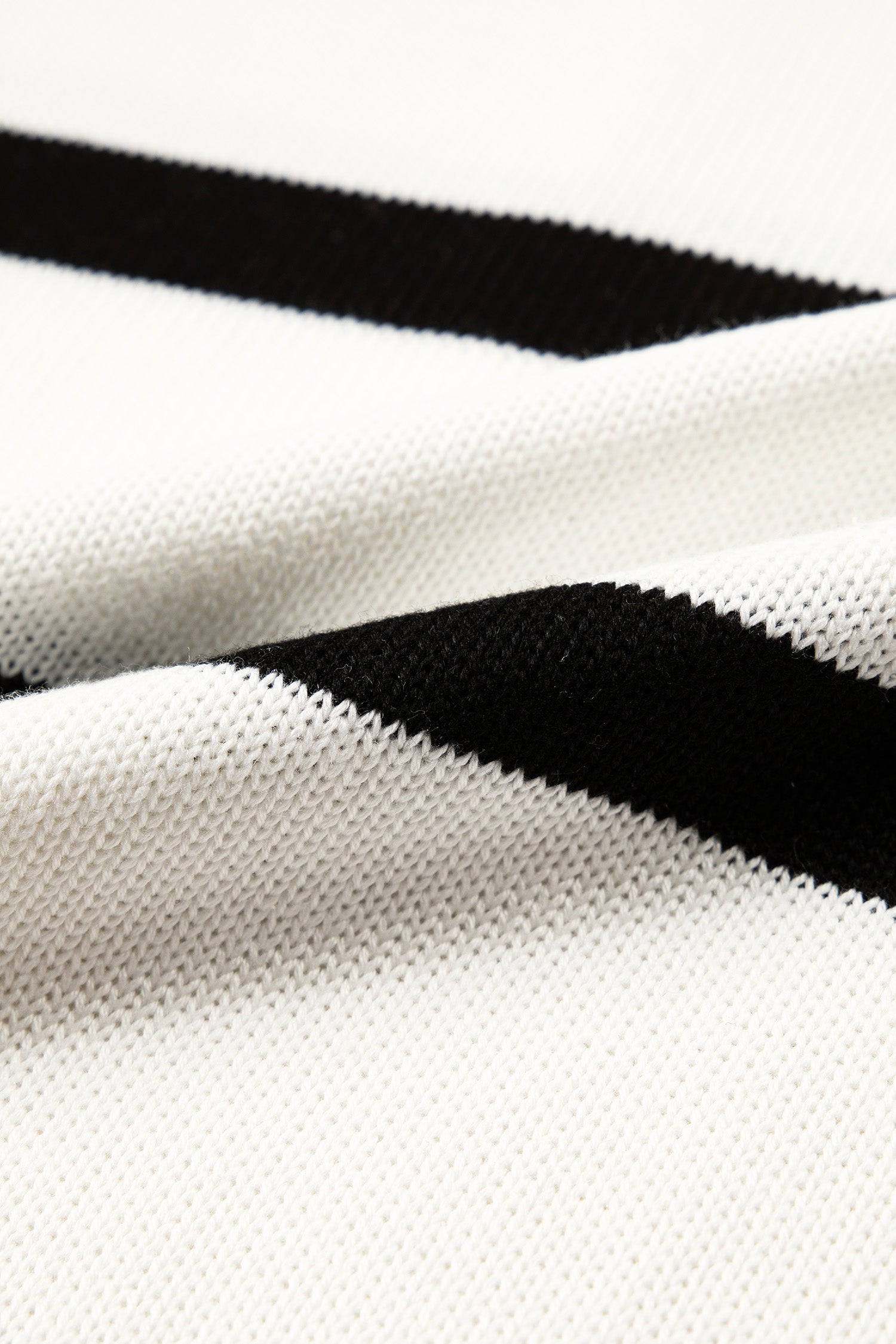 Close-up of a knit fabric with a white base and bold black diagonal stripes.