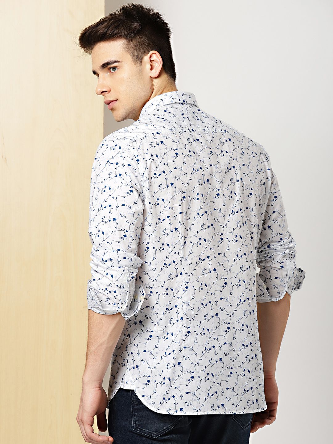 Man wearing a white floral patterned shirt against a plain background