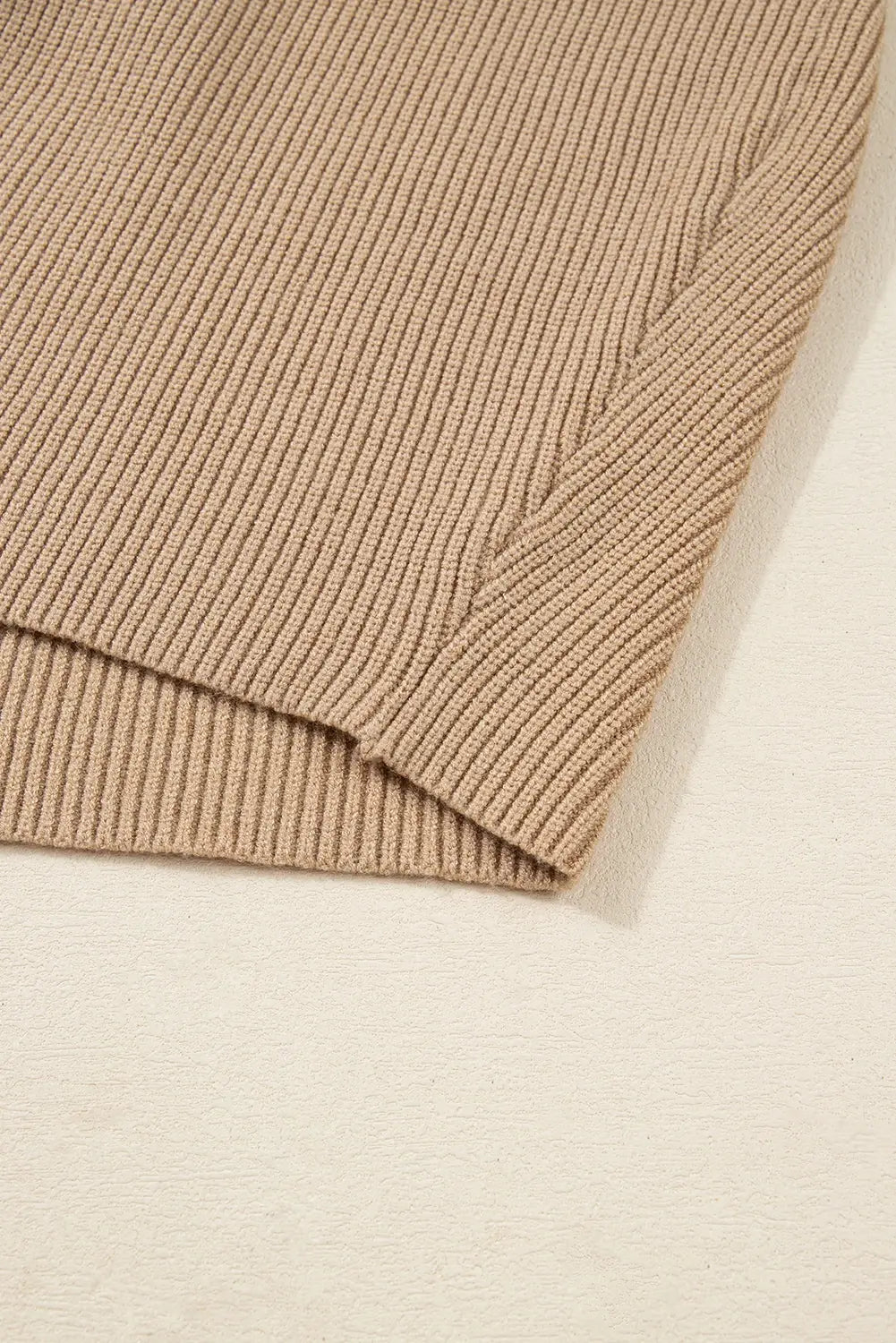 Close-up of a beige ribbed knit fabric on a light beige background