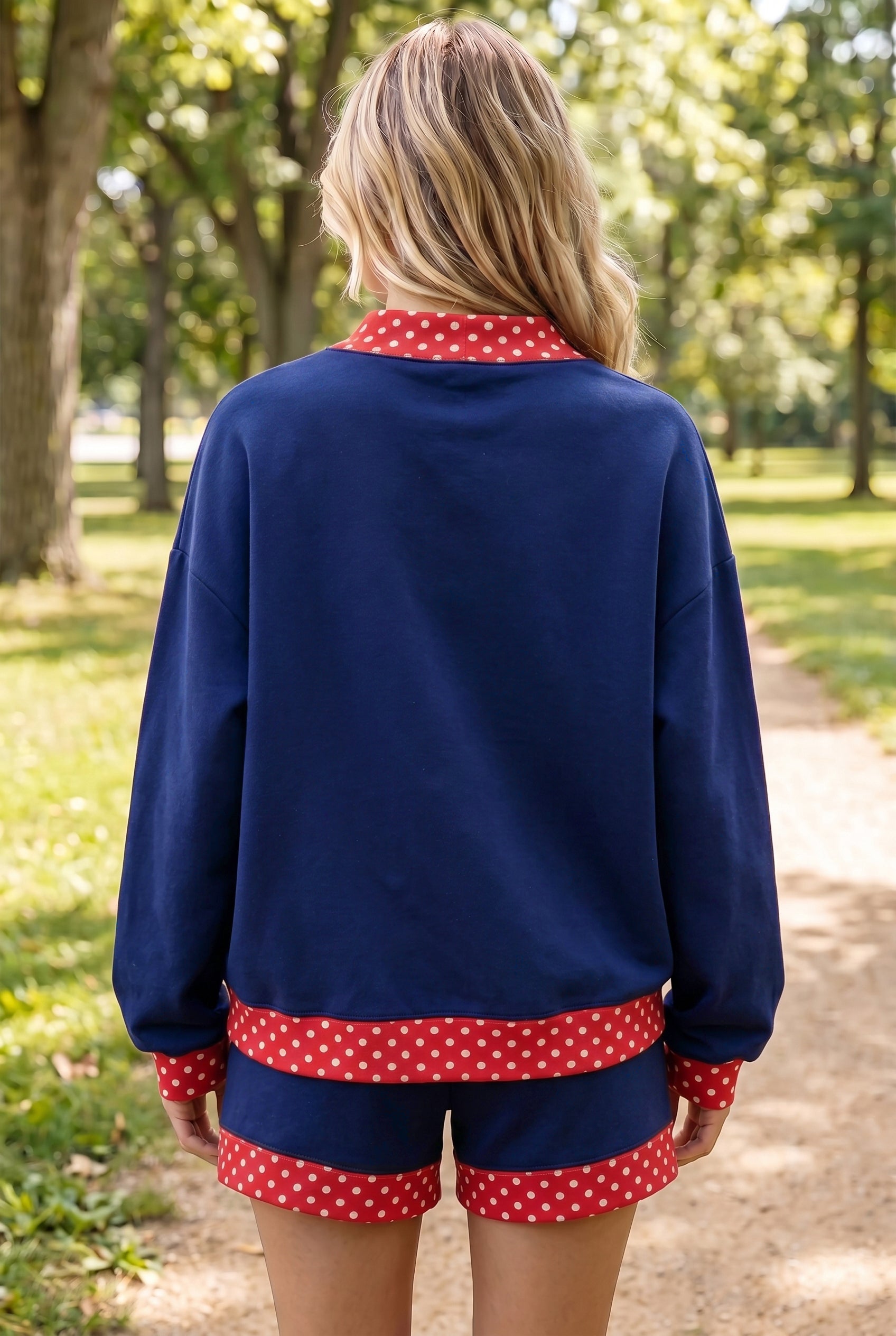 Woman viewed from behind in navy top and matching shorts with red-white polka-dot trim.