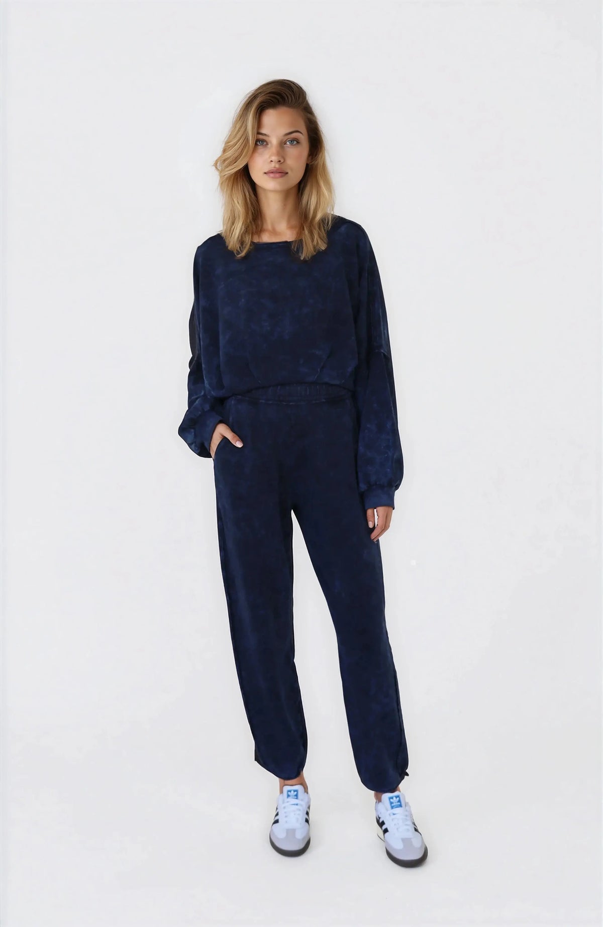 Woman wearing a navy blue outfit with white sneakers on a white background
