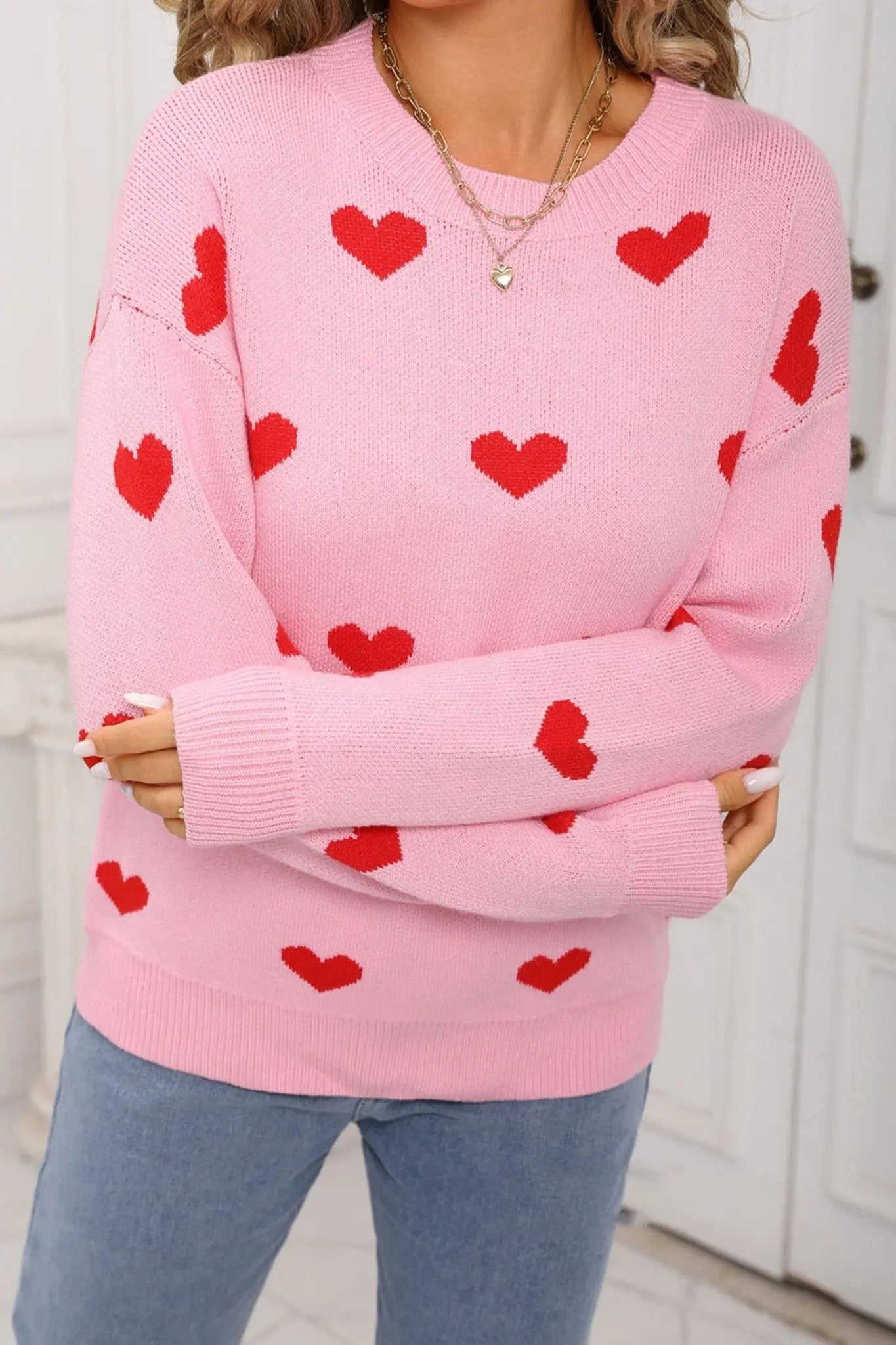Person wearing a pink sweater with red heart patterns in a kitchen setting
