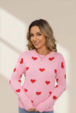 Woman wearing a pink sweater with red heart patterns on a beige background