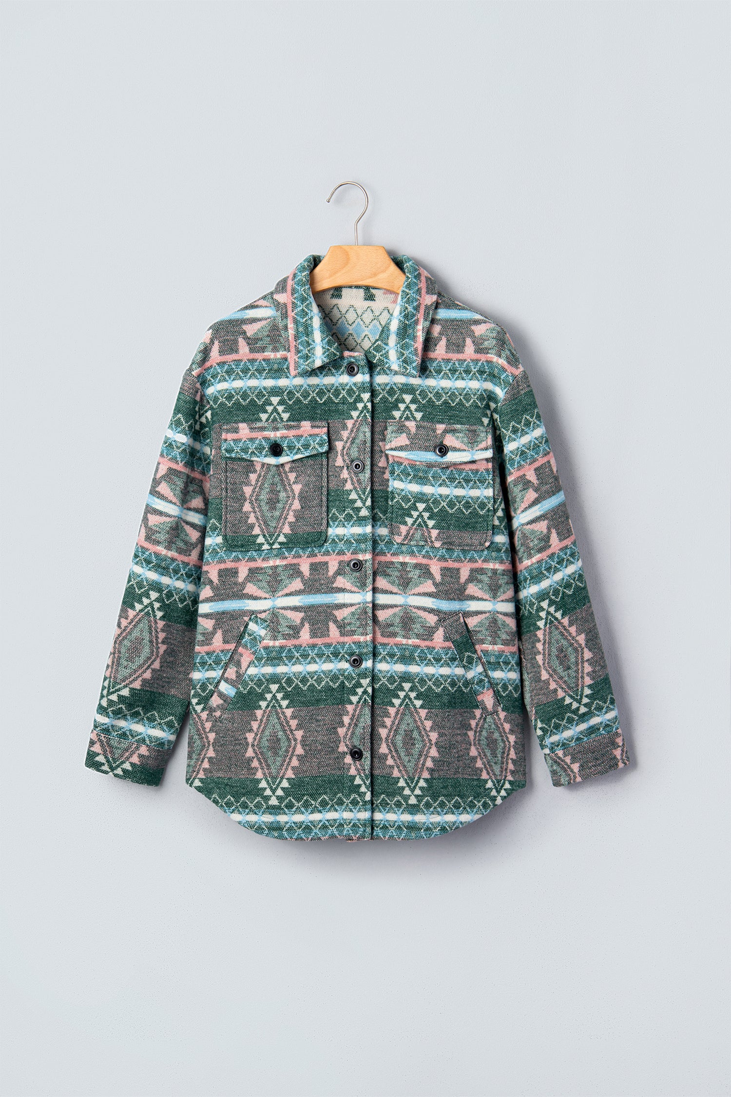A long-sleeve button-front jacket with a colorful geometric tribal pattern, hanging on a wooden hanger against a light gray background.