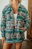 A woman wearing a long-sleeve button-front overshirt with a green, pink, and gray geometric southwestern pattern, layered over a white tank top.