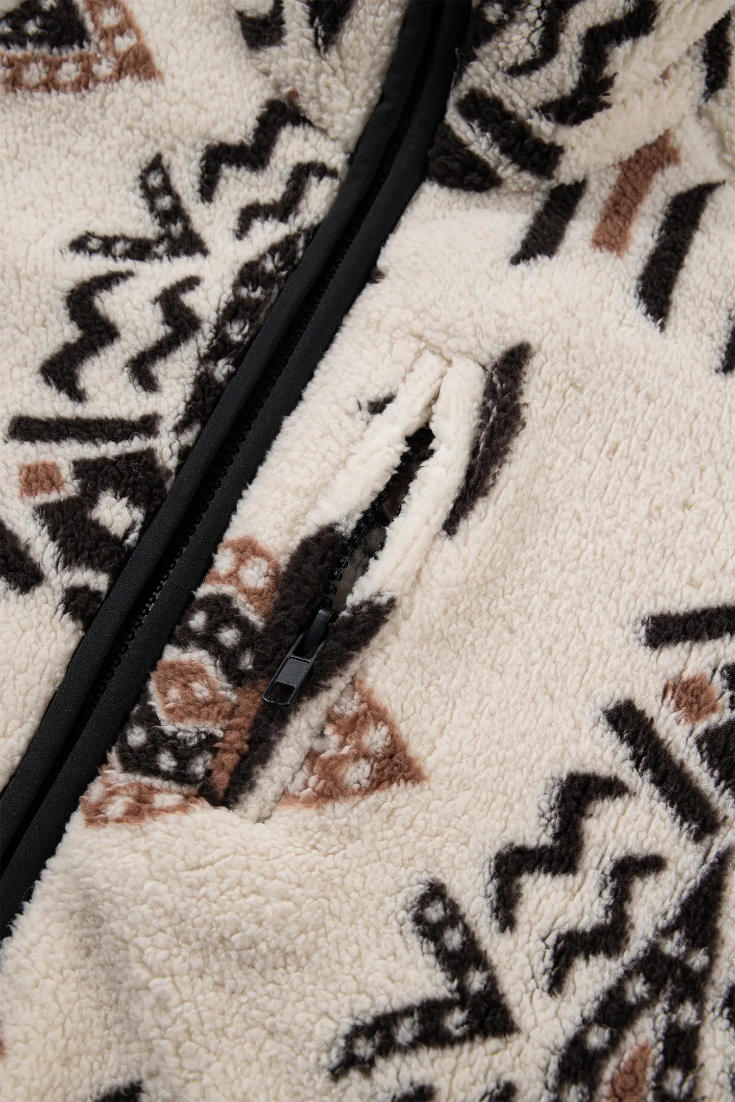Close-up of a sherpa fleece zip jacket featuring a black and brown geometric tribal pattern on an off-white background.