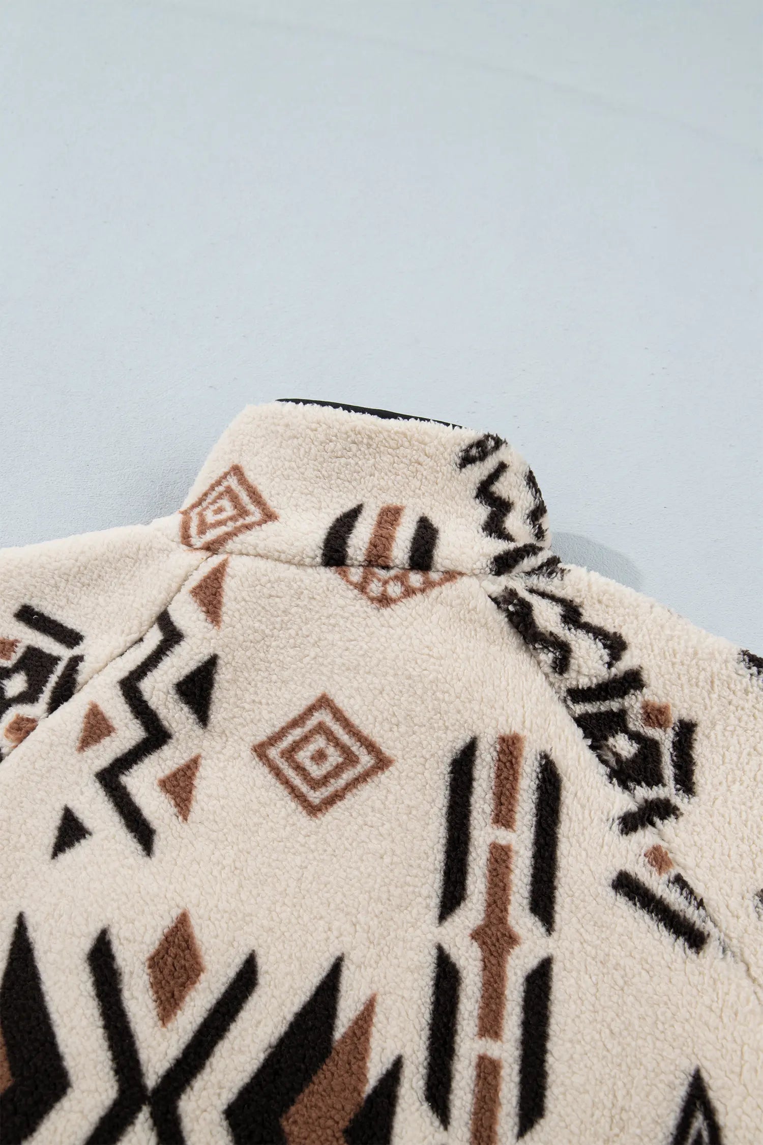Close-up of a fleece garment with a Southwestern geometric pattern in black, brown, and cream.