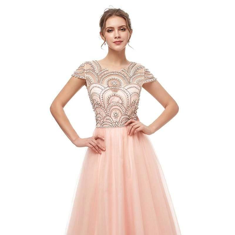 Woman wearing a pink evening gown with intricate top design on a white background