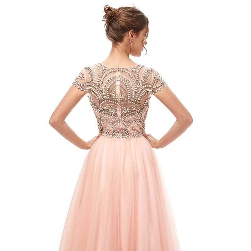 Woman wearing a pink evening gown with intricate beading on a white background