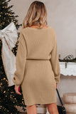 Woman wearing a beige ribbed dress in a festive setting with a decorated Christmas tree and fireplace.