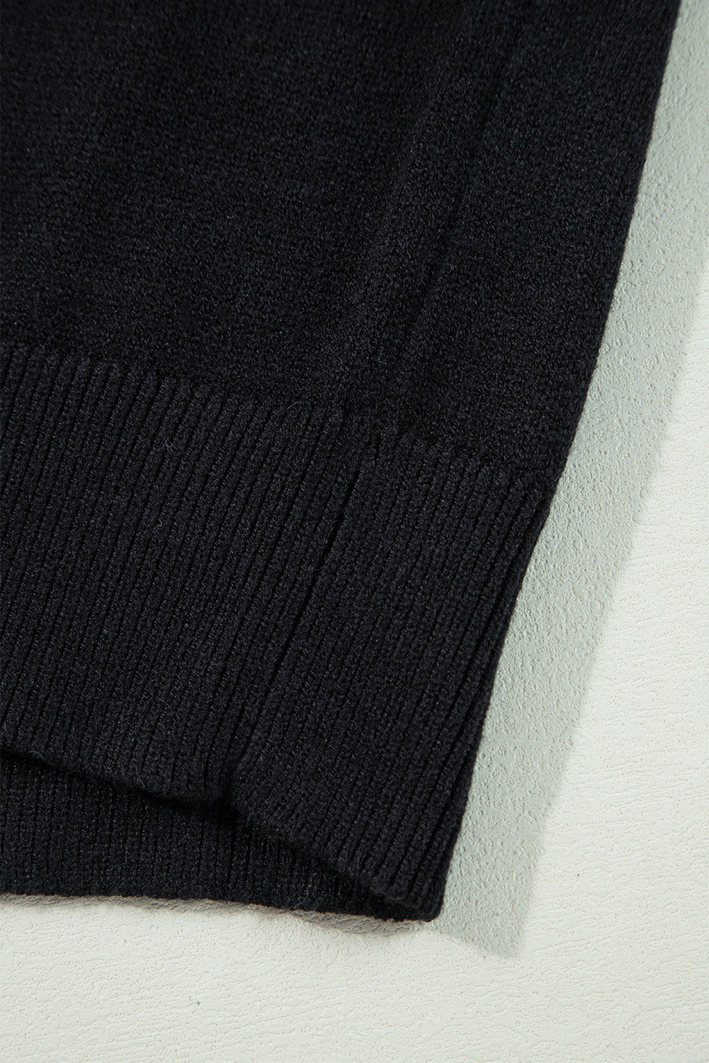 Close-up of a black sweater on a light gray background
