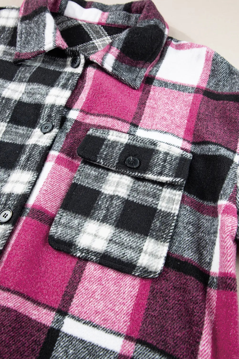 Close-up of a plaid shirt with pink, black, and white pattern.