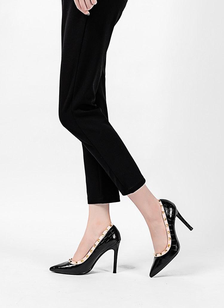 Person wearing black high-heeled shoes and black pants on a white background