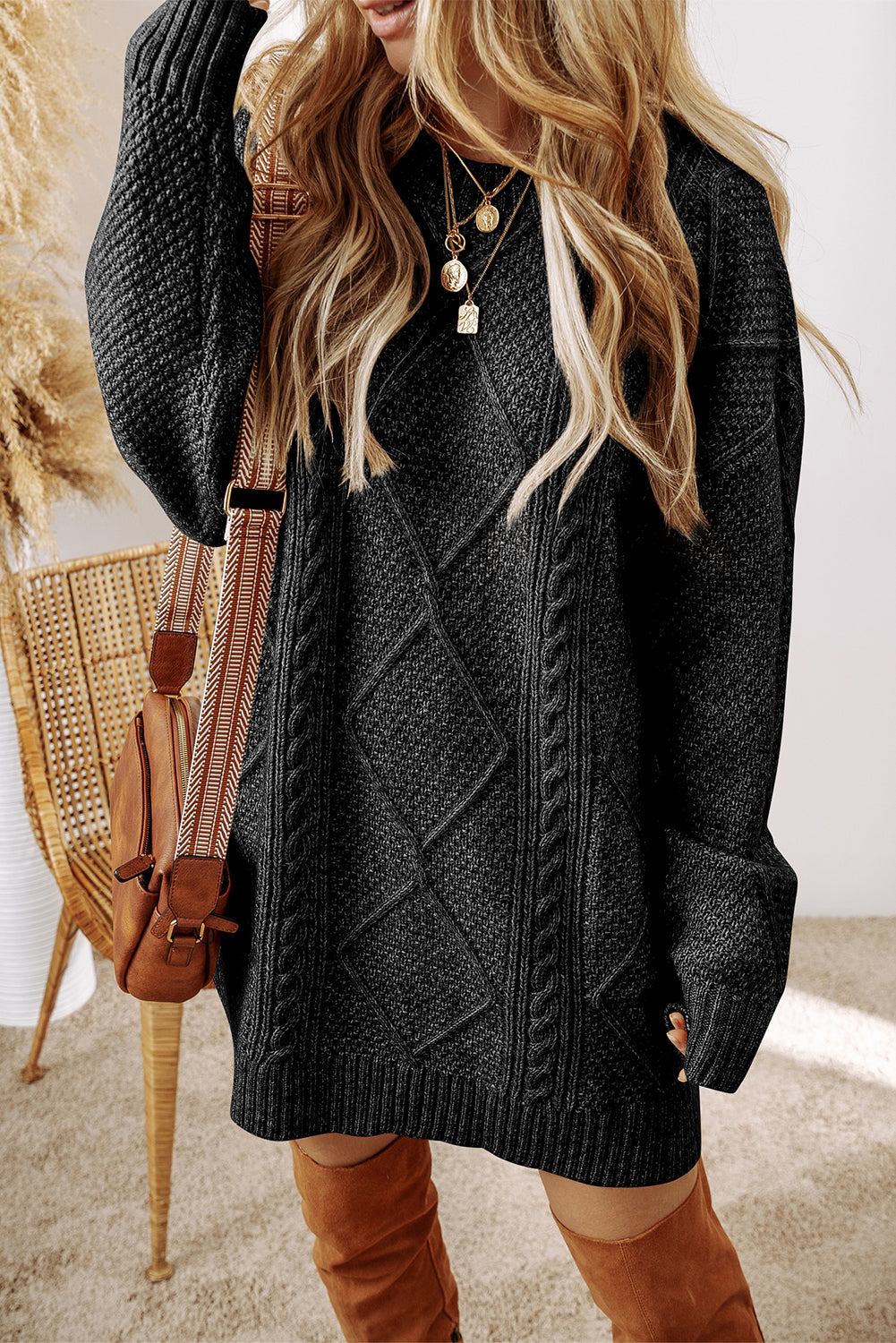Woman wearing a dark gray cable knit sweater with brown boots and a brown bag.