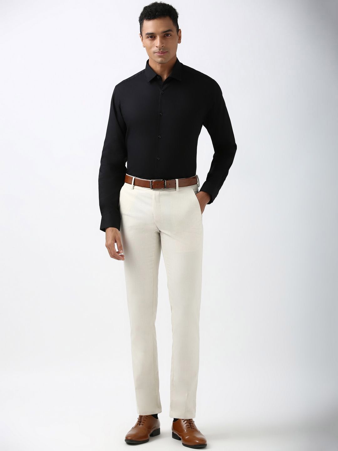 Man wearing a black shirt, white pants, and brown shoes on a white background
