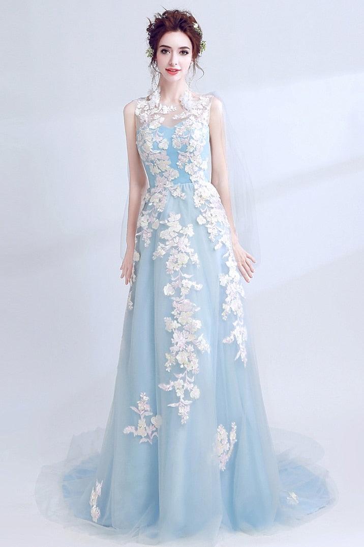Woman wearing a light blue evening gown with floral lace details on a white background