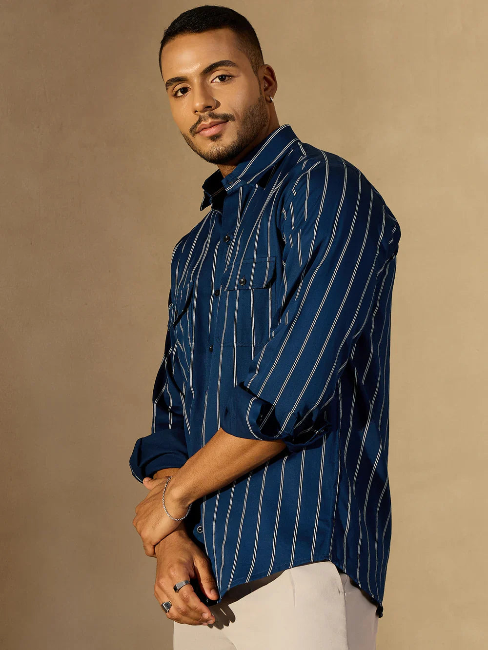 Man wearing a blue striped shirt against a beige background