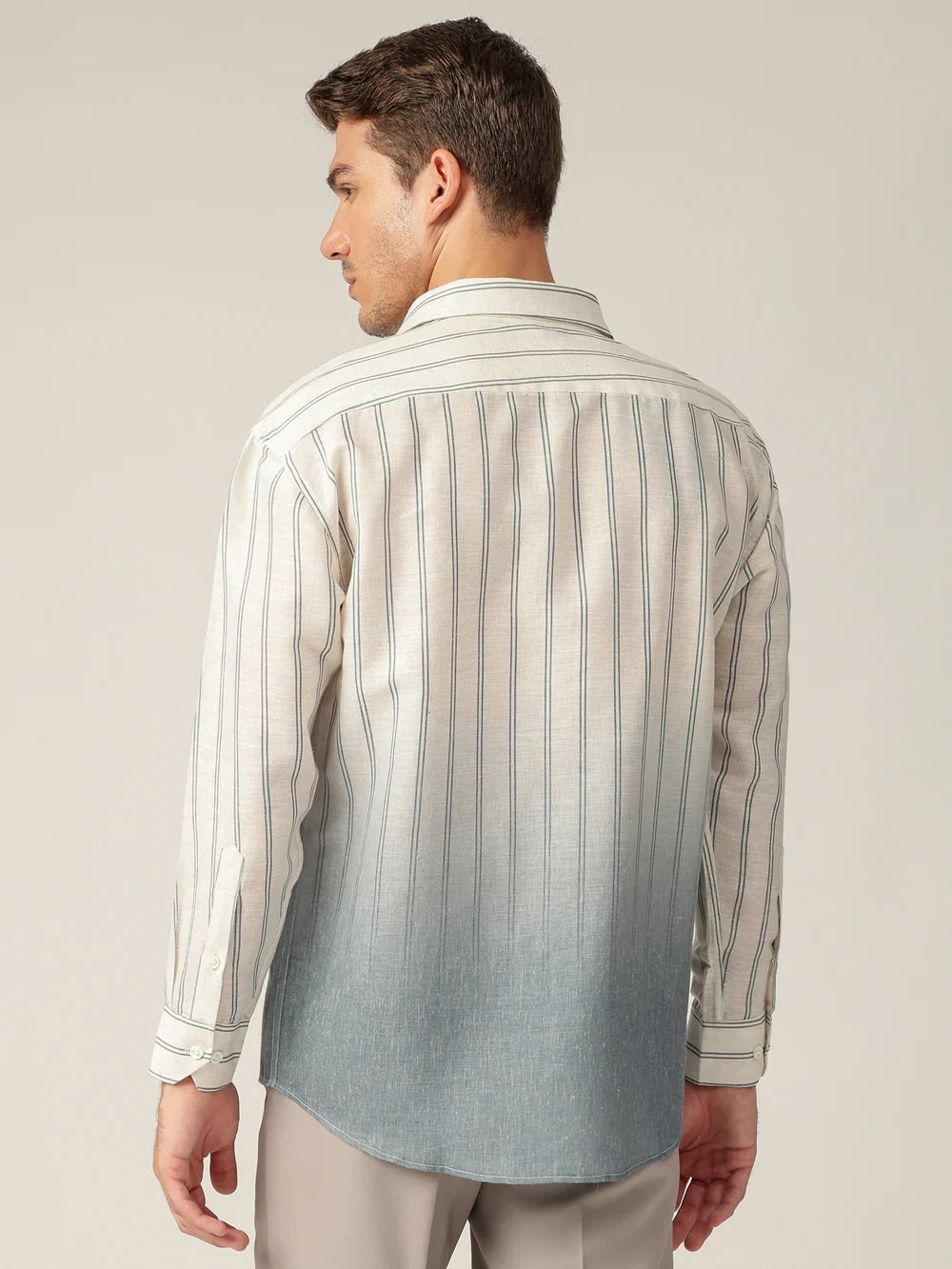 Man wearing a striped shirt with a gradient effect from beige to blue on a neutral background