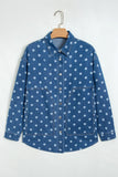 Blue denim shirt jacket with white polka dots hanging on a wooden hanger against a white background.