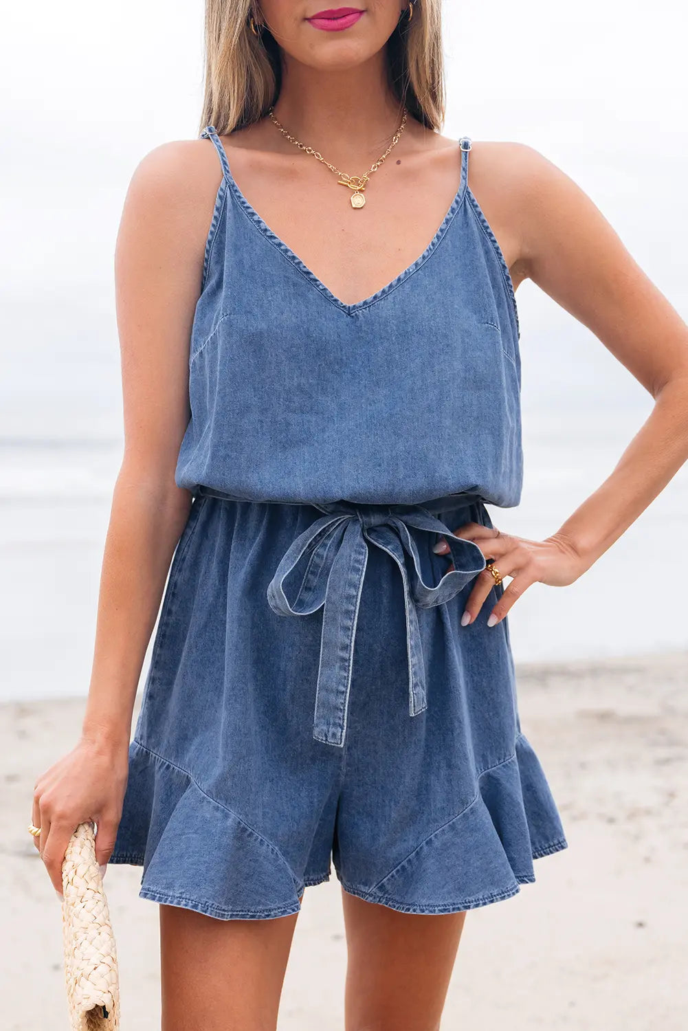 Woman wearing a denim romper on a beach