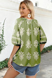 Woman wearing a green blouse with white patterns outdoors.