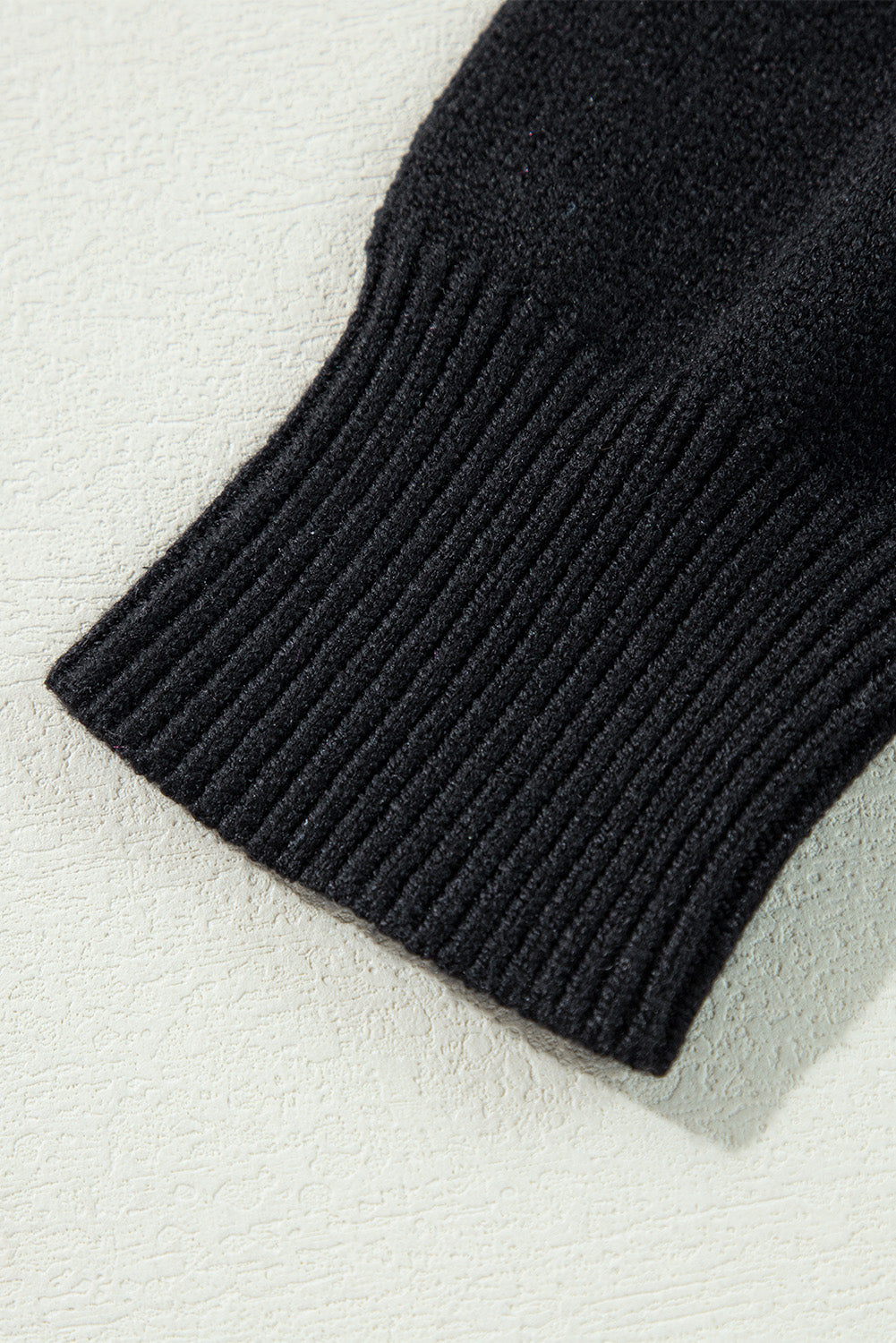 Close-up of a black knitted sleeve on a light gray background