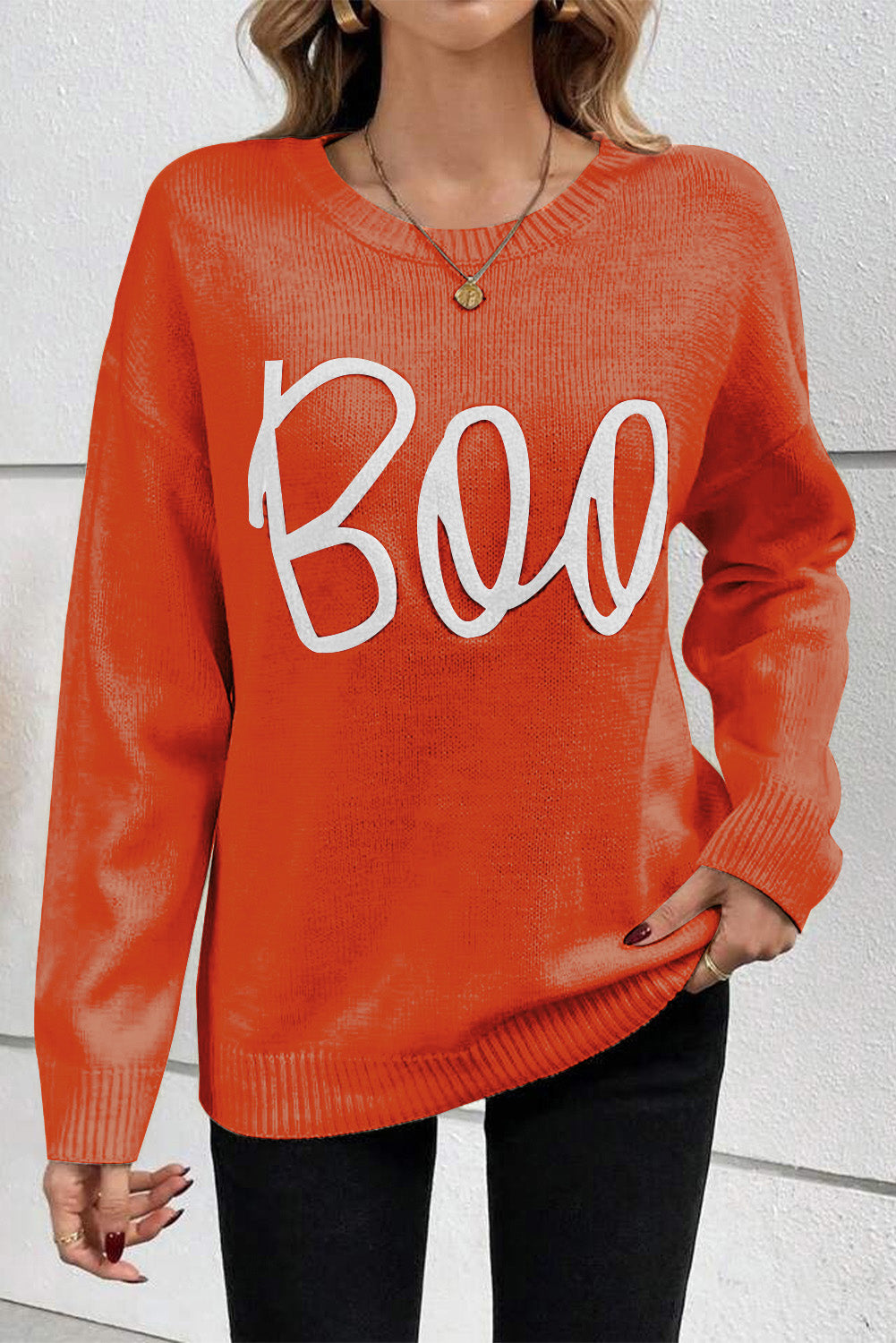 Person wearing an orange sweater with 'BOO' text against a white background