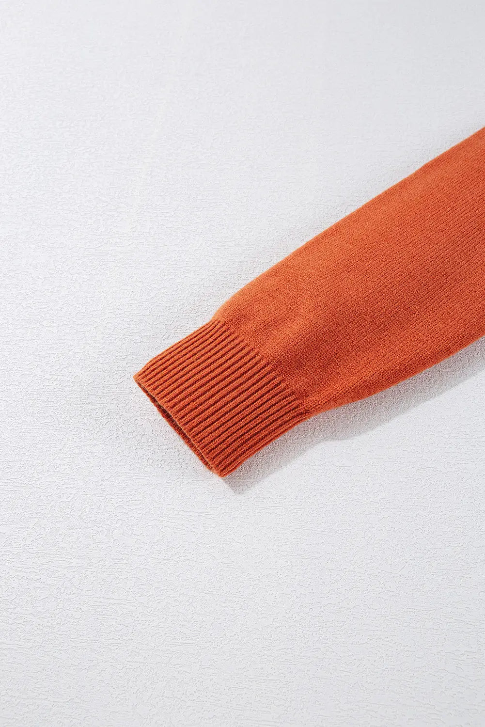 Close-up of an orange sweater sleeve on a white background