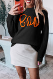 Person wearing a black sweater with orange 'Boo' text, taking a mirror selfie.
