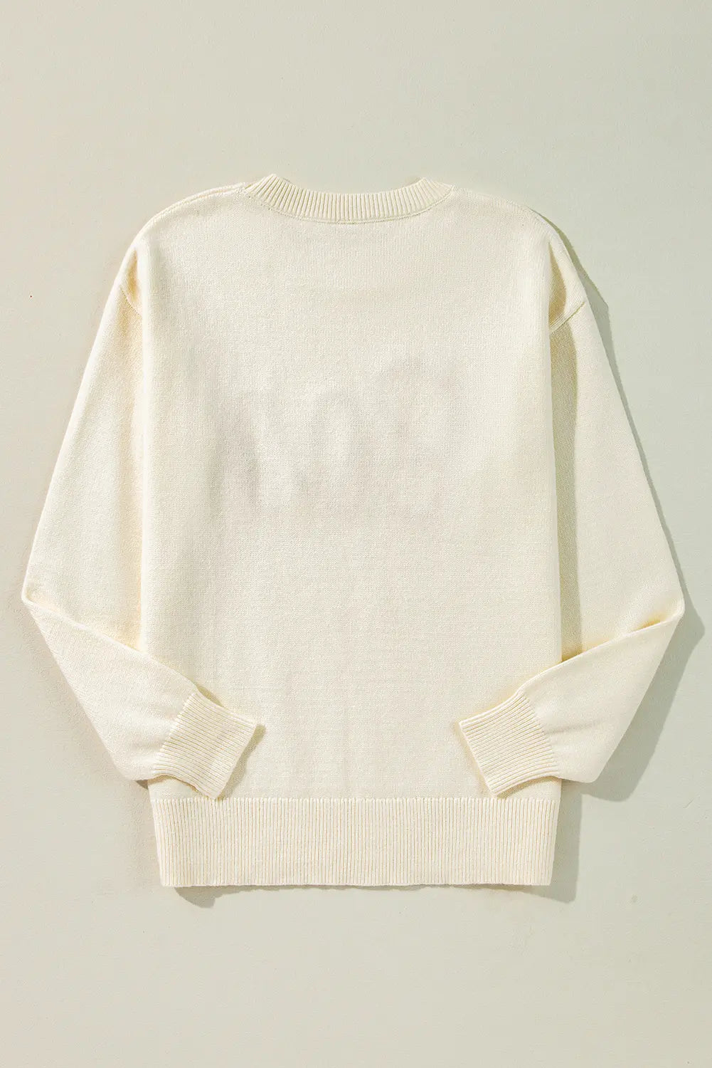 Off-white knit sweater with subtle tonal back graphic, laid flat on beige background.