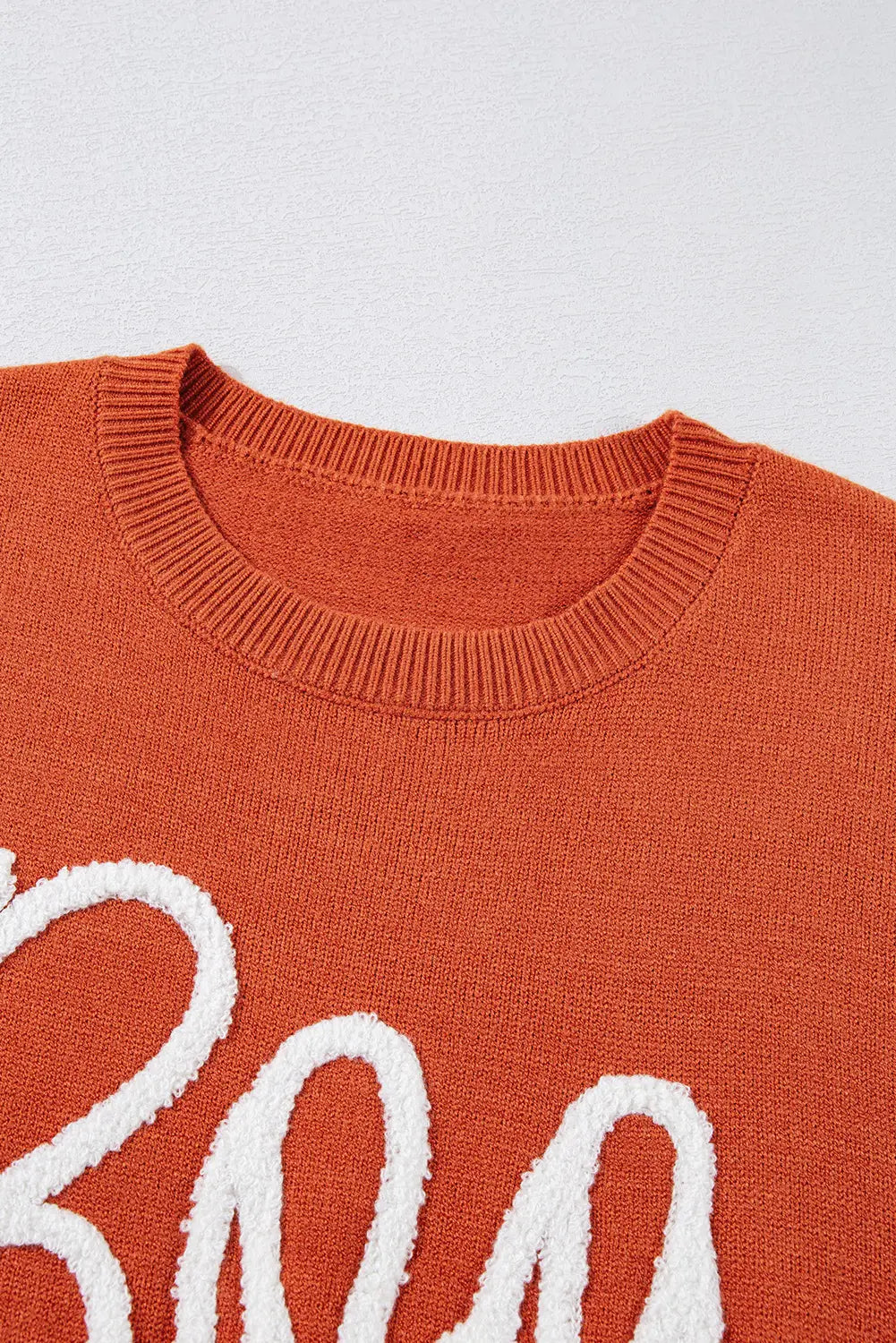 Close-up of an orange sweater with white text on a light gray background