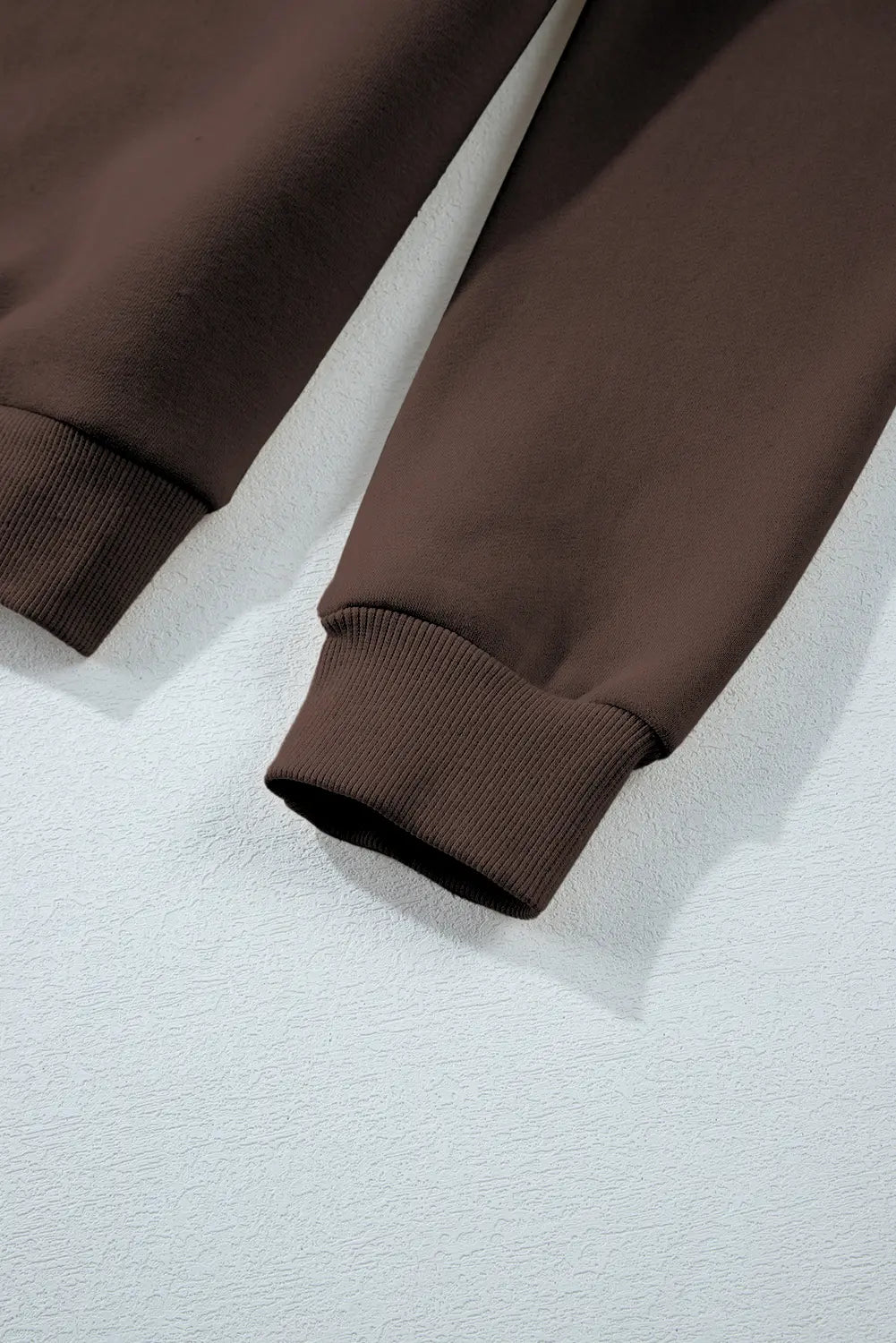 Brown sweatpants on a light gray textured surface