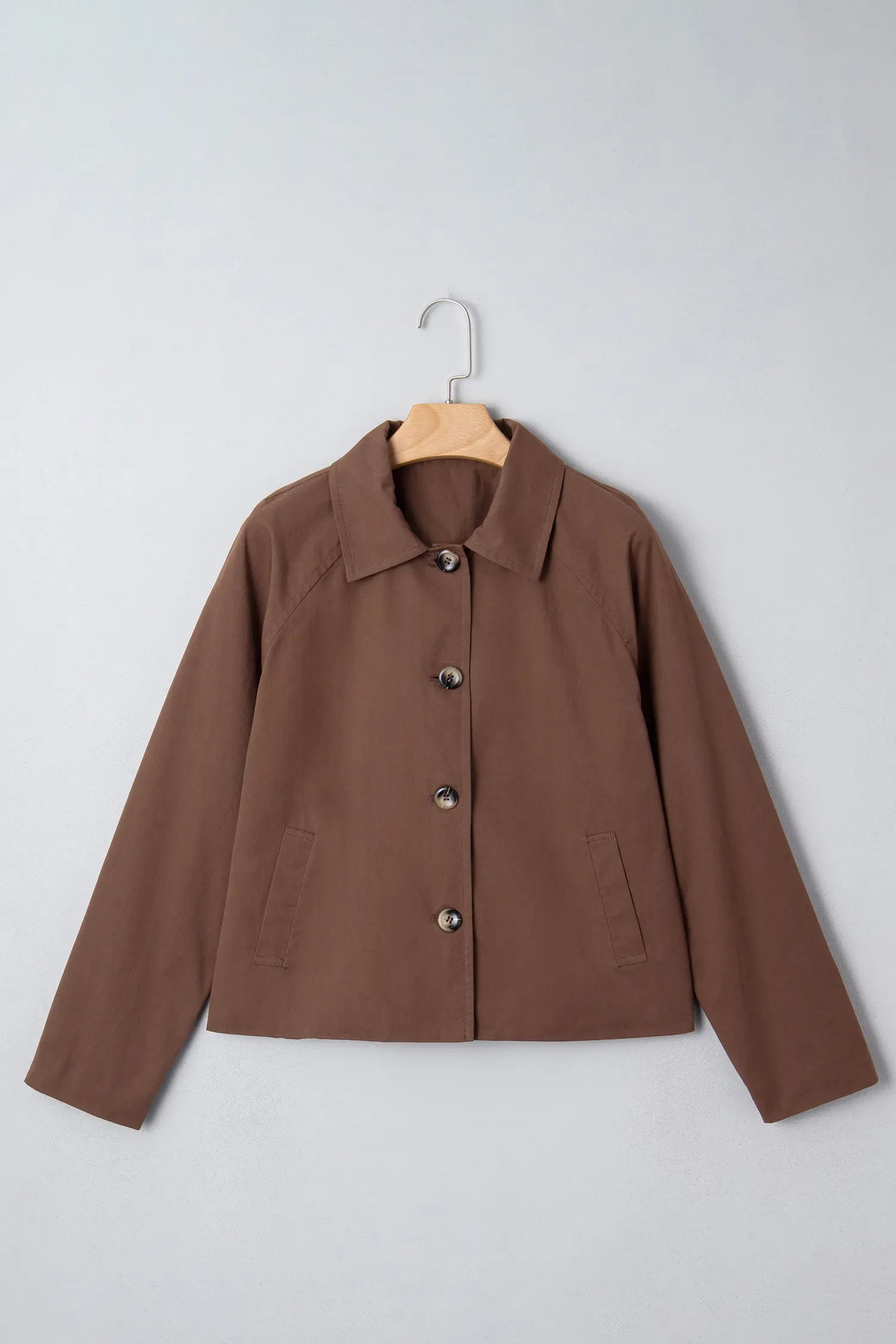 Brown jacket on a hanger against a light gray background