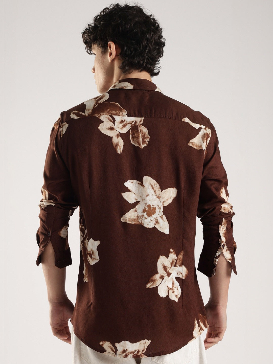 Man wearing a brown floral shirt against a white background