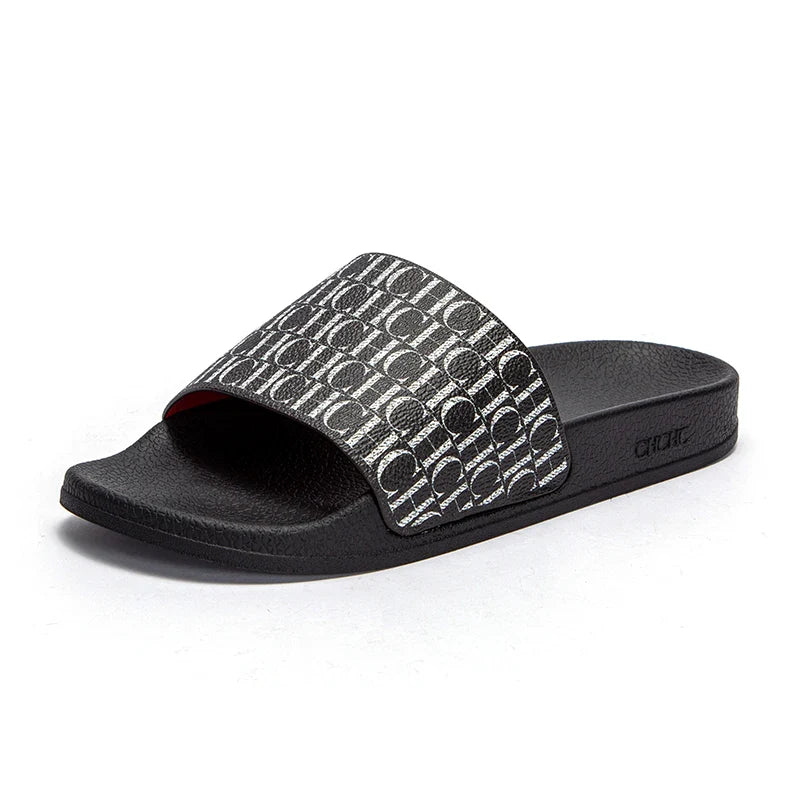 Black slide sandal with patterned strap on a white background