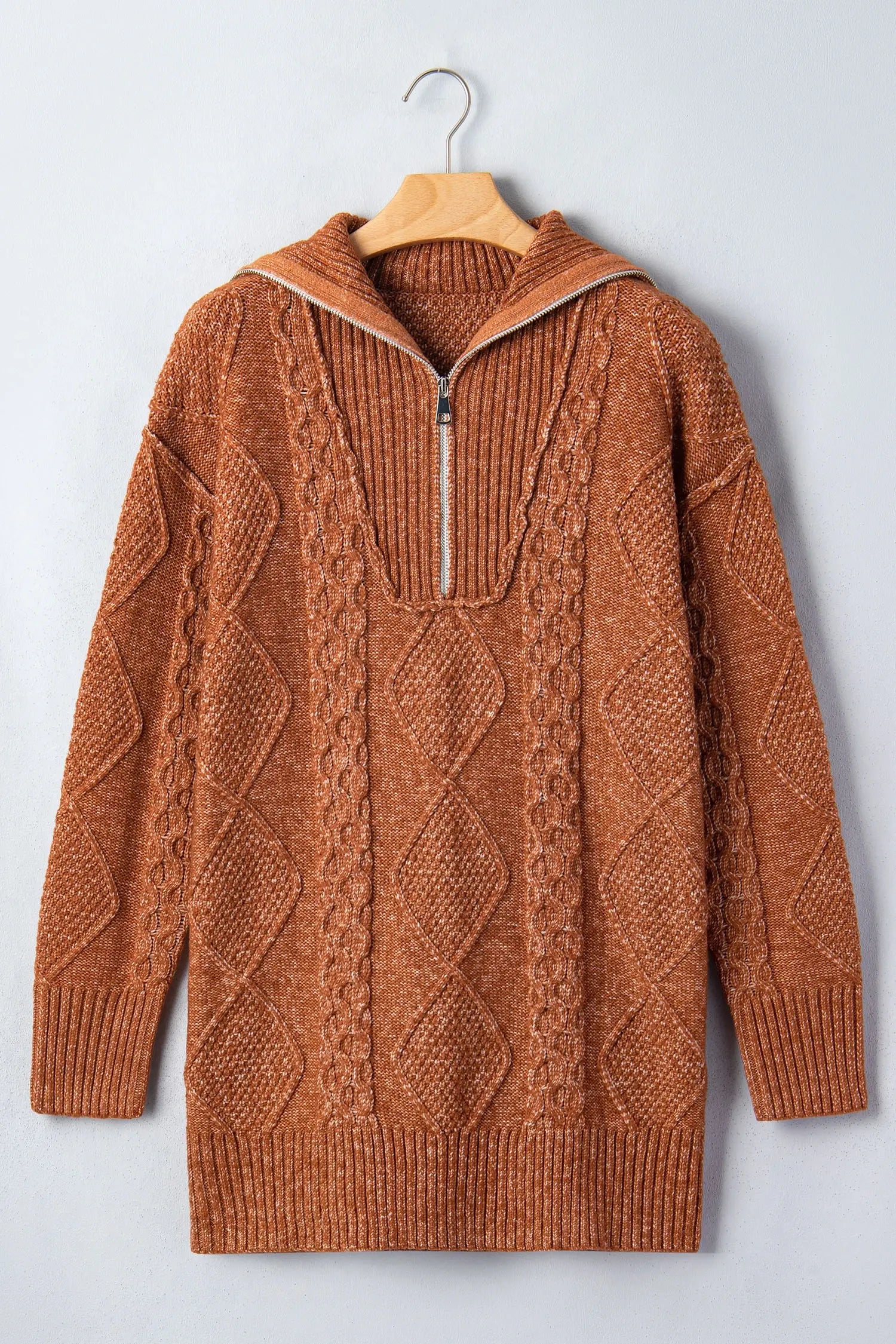 Rust-brown cable-knit hooded half-zip sweater on wooden hanger against light gray background.