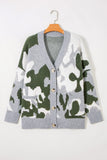 A gray knit cardigan sweater with a green and white camouflage pattern, featuring a V-neck, button closure, and front pockets, hanging on a wooden hanger against a light gray background.