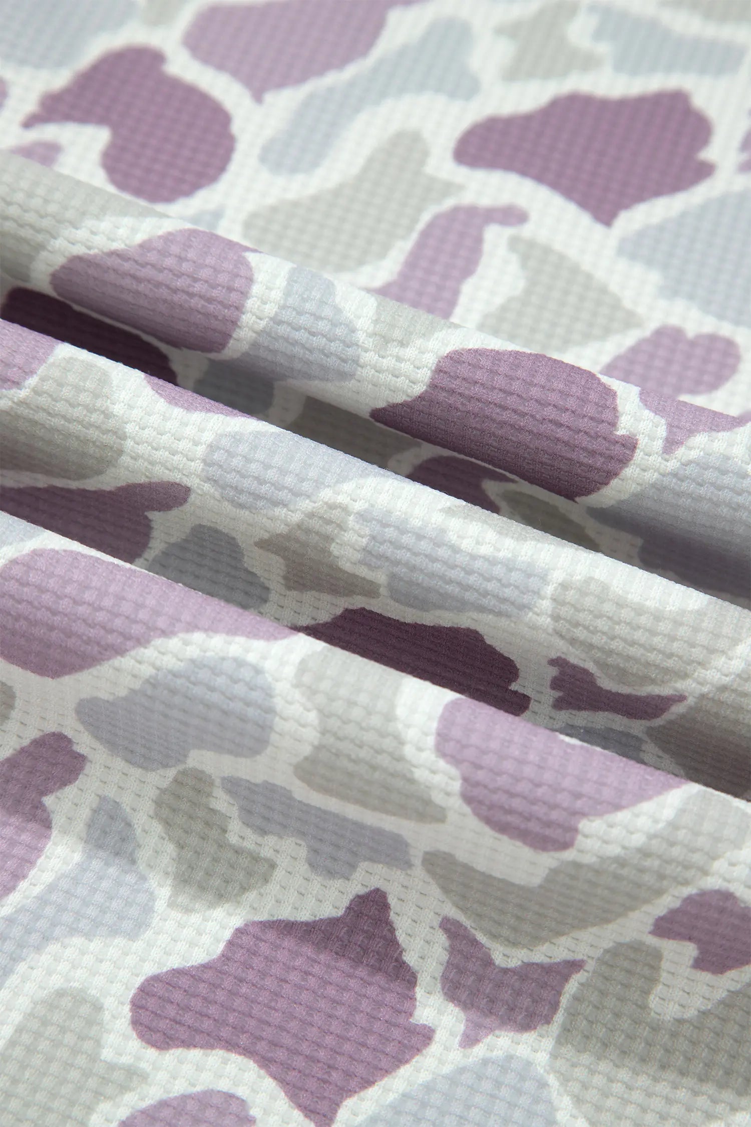 A close-up of a textured fabric with an abstract organic wavy pattern in shades of lavender purple, light gray, and white.