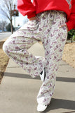 Person wearing a red sweatshirt and patterned pants on a sidewalk.