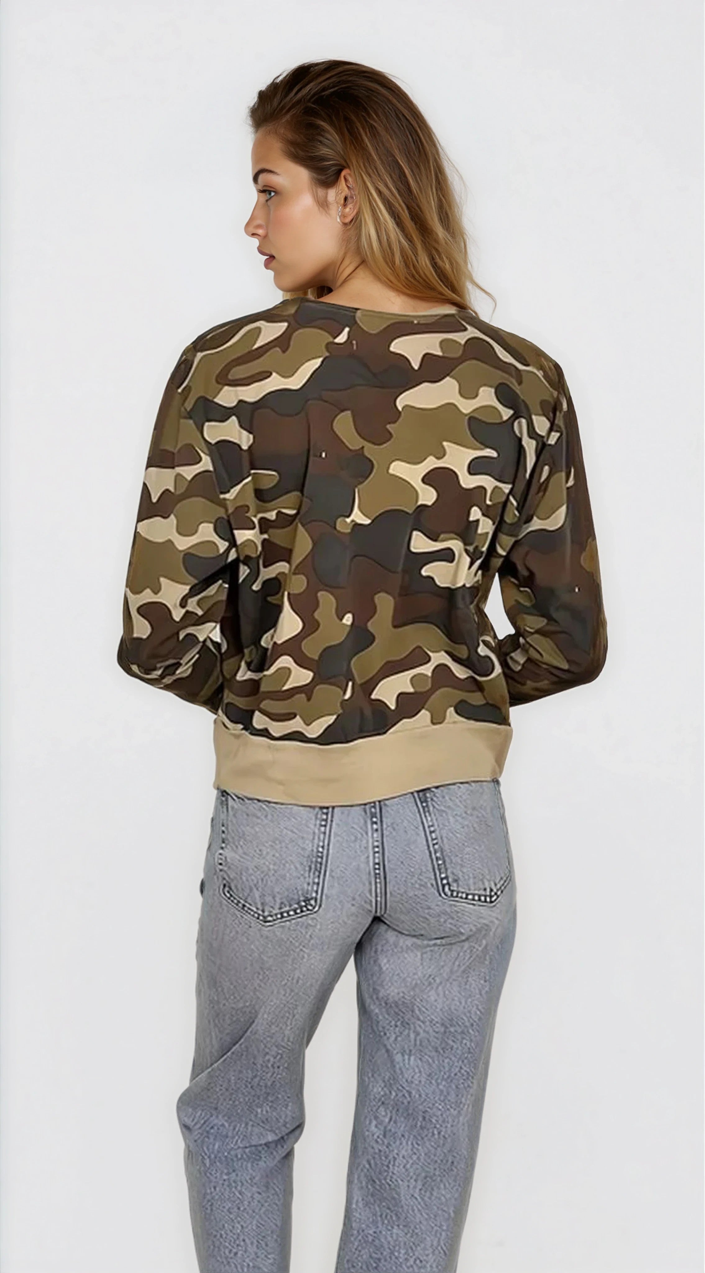 Person wearing a camouflage sweater and light blue jeans on a white background