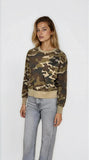 Woman wearing a camouflage sweater and jeans on a white background