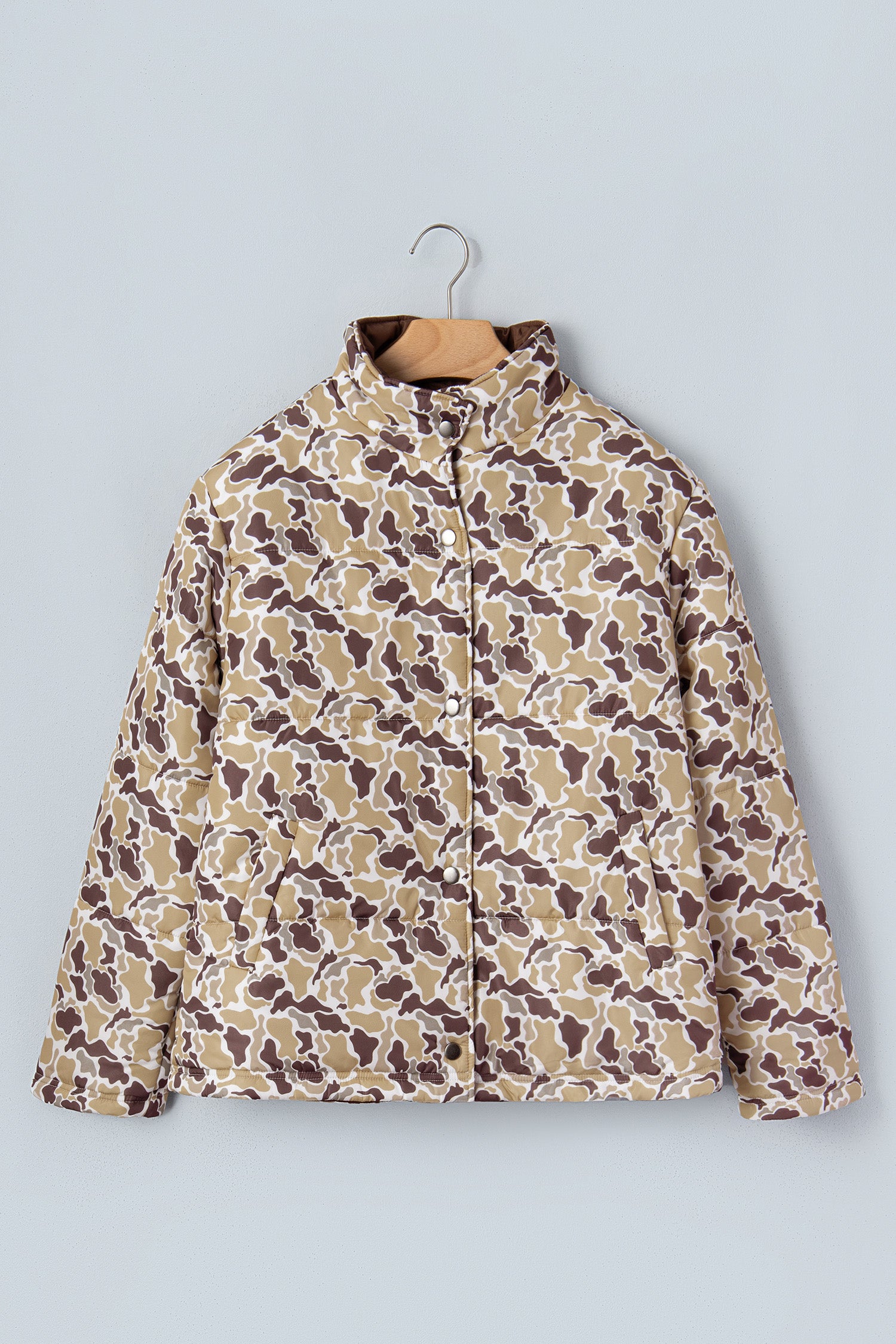 Long-sleeve brown, beige, and white abstract organic pattern quilted jacket on hanger against light gray.