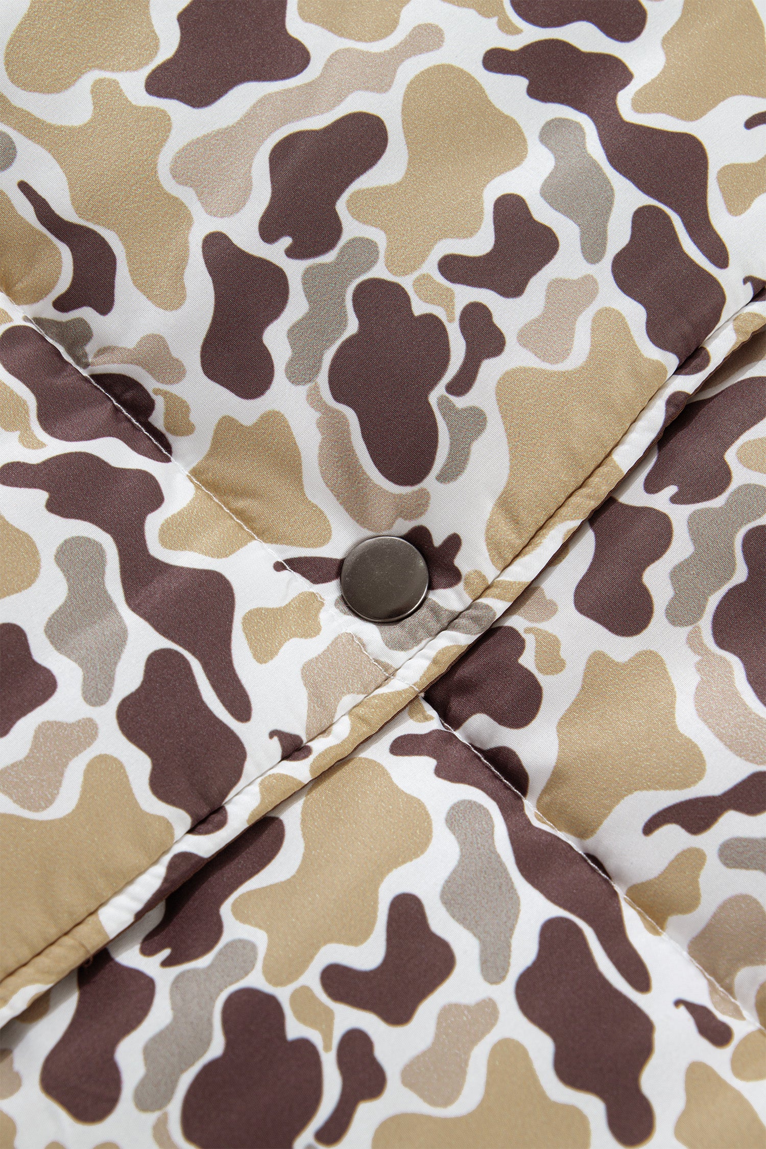 Close-up of a quilted puffer jacket showing a brown, beige, and white camouflage.