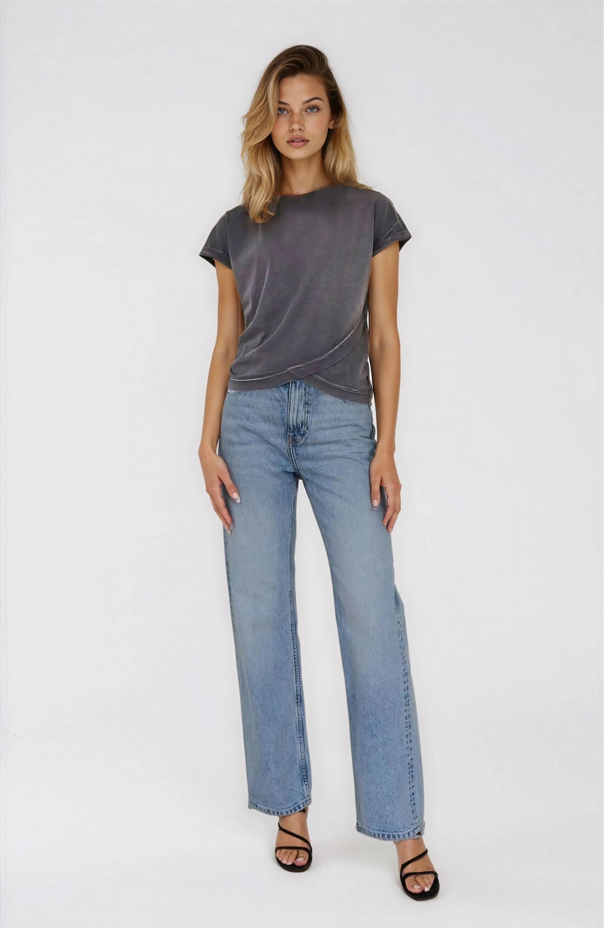 Woman wearing a gray t-shirt and light blue jeans on a white background